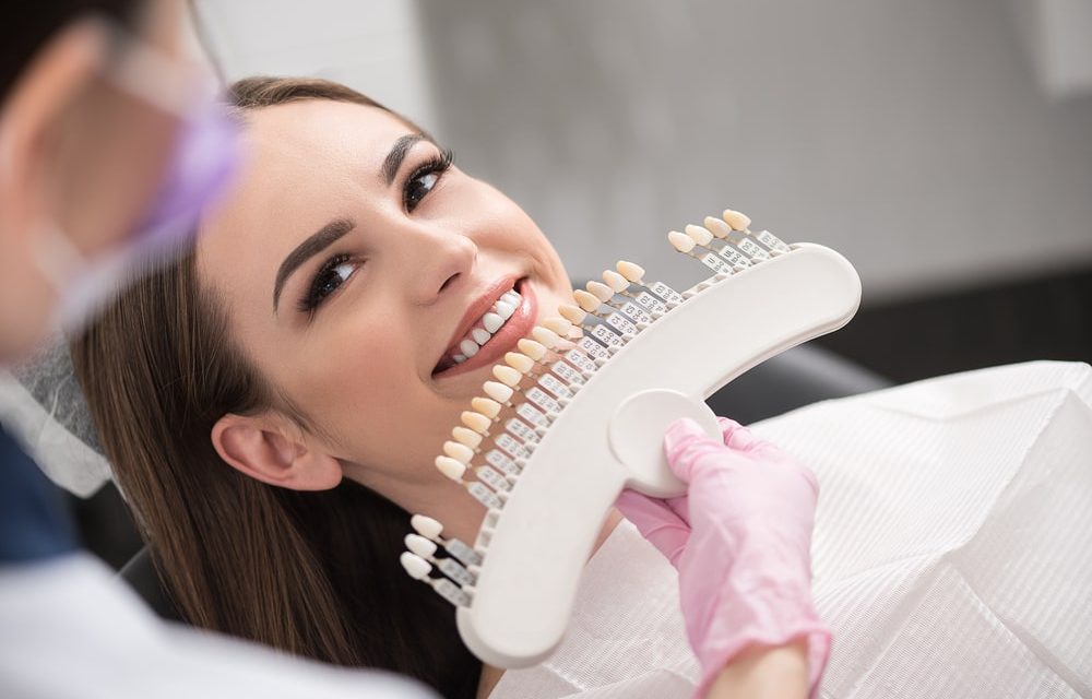 Dentist Comparing A Set Of Dental Crowns To Womans Teeth
