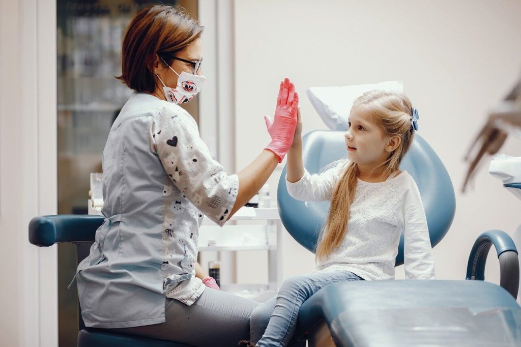 ​Pediatric dentist cheering a girl